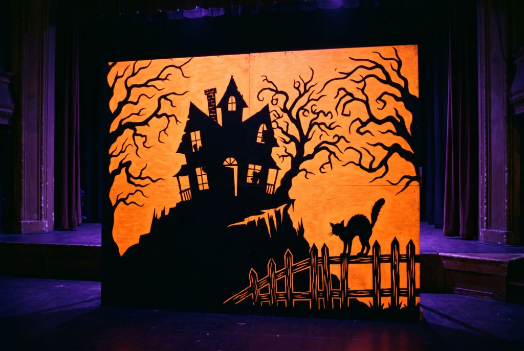 Schwarze Silhouetten vor oranger Neonfarbe im Schwarzlicht (Stimmungsbild, KI-generiert)
